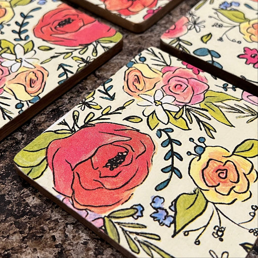 Set of four floral, wooden coasters sitting on granite surface.