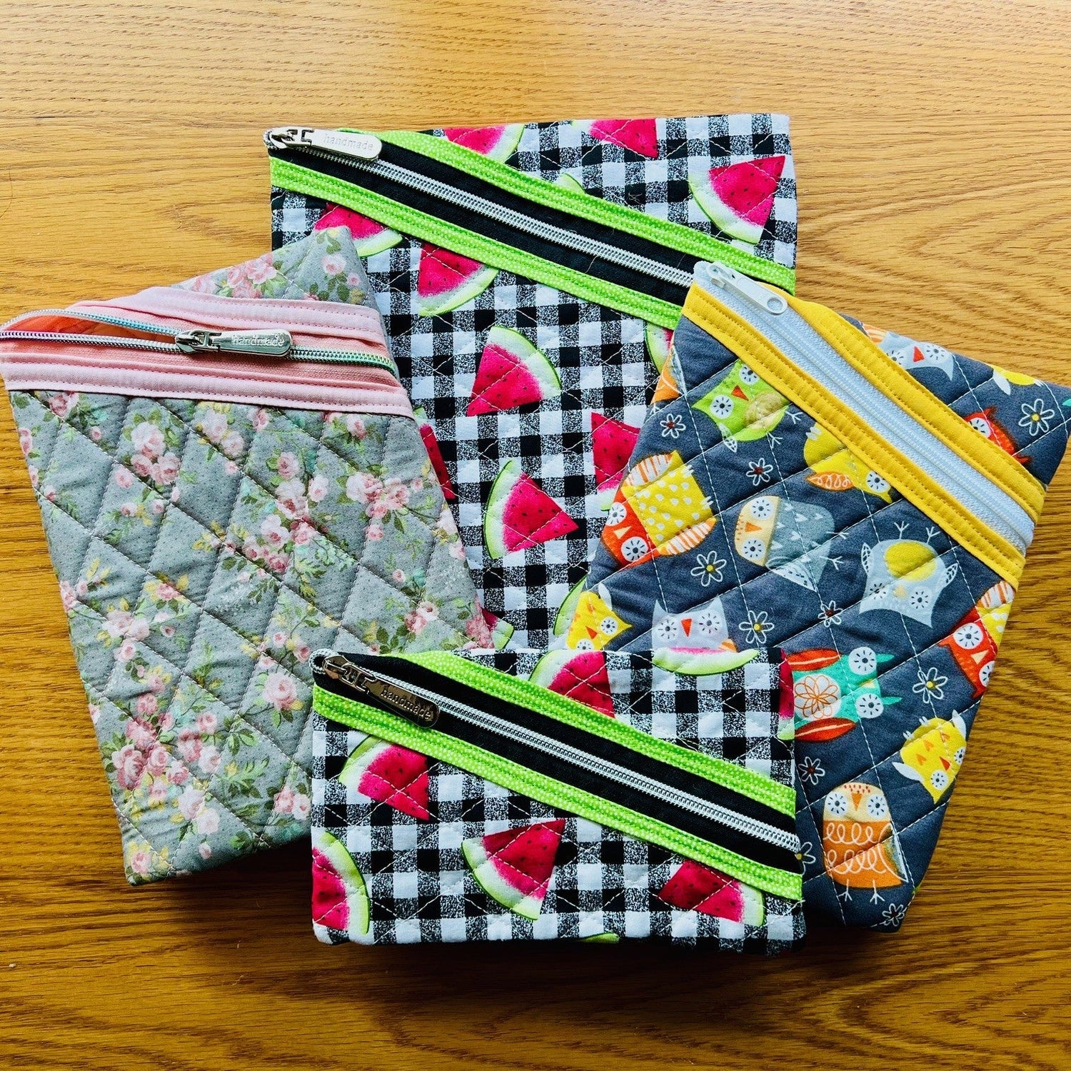 Several zipper pouches displayed on a wooden surface, each featuring different sizes and patterns.