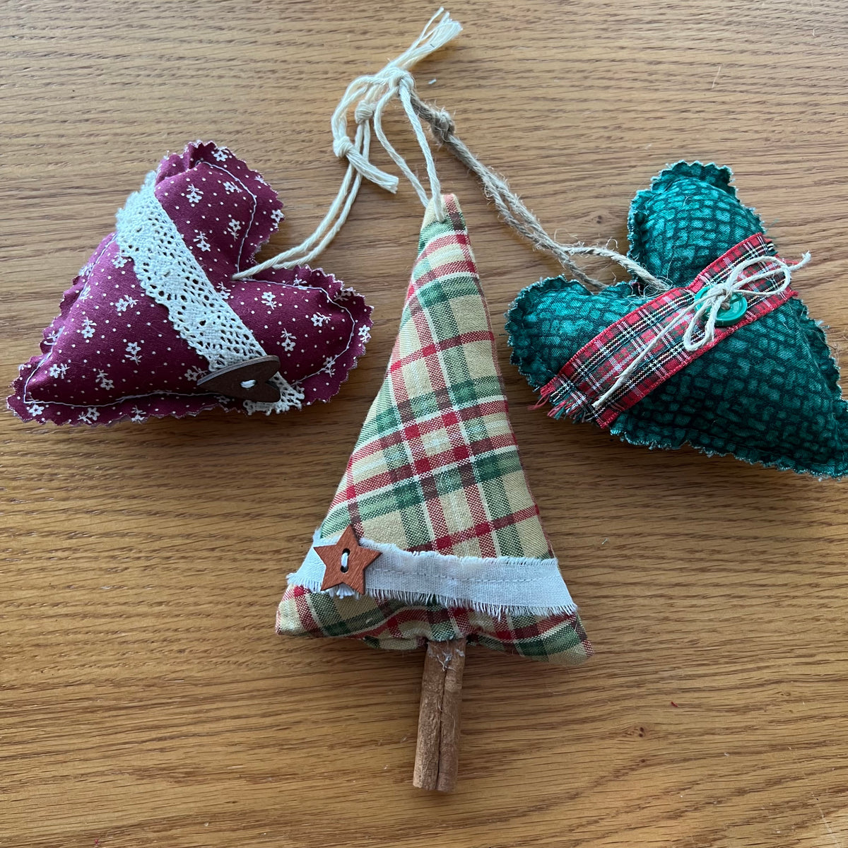 This photo shows a mystery style curated combination of Eclectic Spruce heart and cinnamon tree ornaments. This photo (shown as an example) shows two hearts and one cinnamon tree sitting on a wood surface.