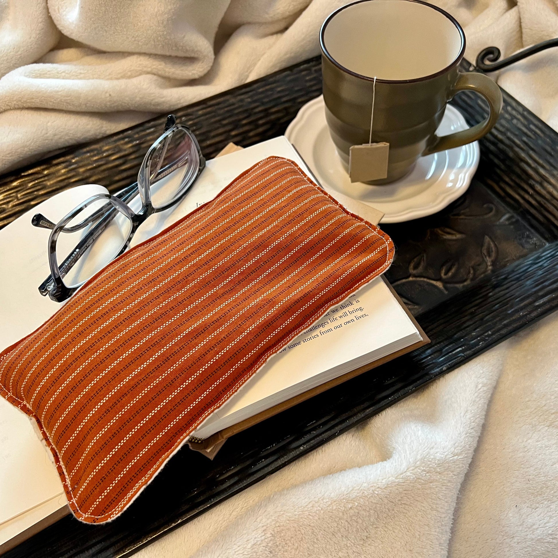 Tray with book, Weighted Eye Pillow, and mug on a soft blanket.