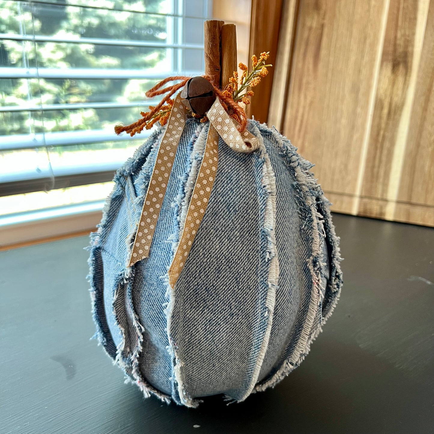 Pumpkin 8: Handmade Eclectic Spruce tall heirloom pumpkin made with light denim fabric and real cinnamon stick stem. It is trimmed with frayed denim seams, polka dot ribbon, rusty jingle bell, twine, and faux floral accents.