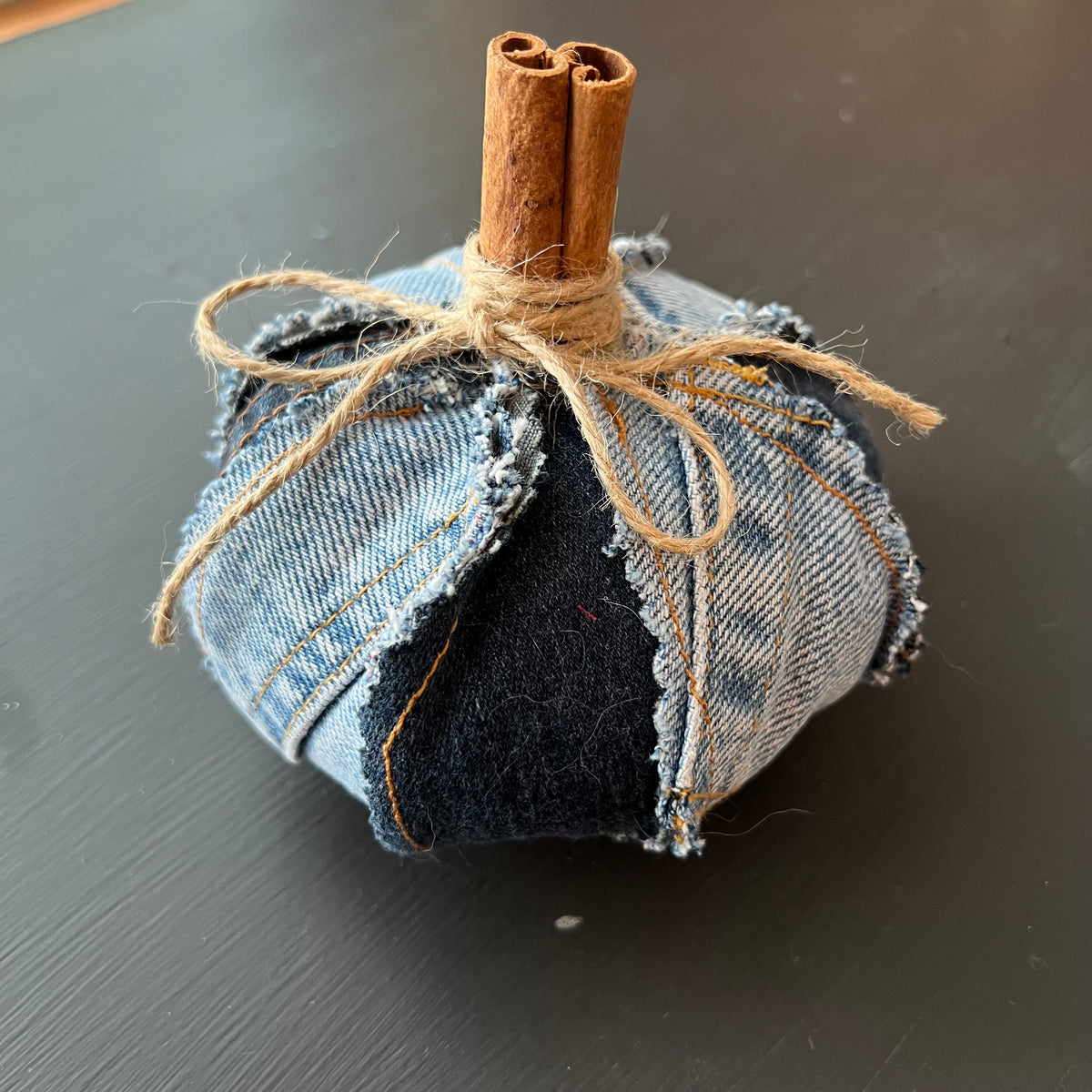 Pumpkin 2: Handmade Eclectic Spruce small pumpkin made with alternating dark and light denim panels with raw edges, accented with a real cinnamon stick stem and twine bow.