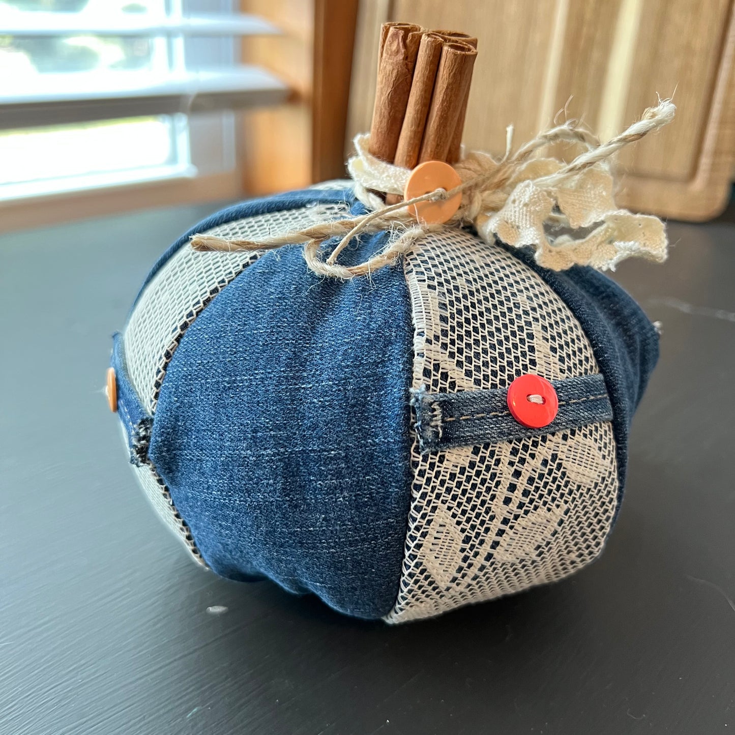 Pumpkin 5: Handmade Eclectic Spruce medium pumpkin made with dark denim fabric and real cinnamon stick stem, accented with cream lace panels, bright accent buttons, and a lace bow.