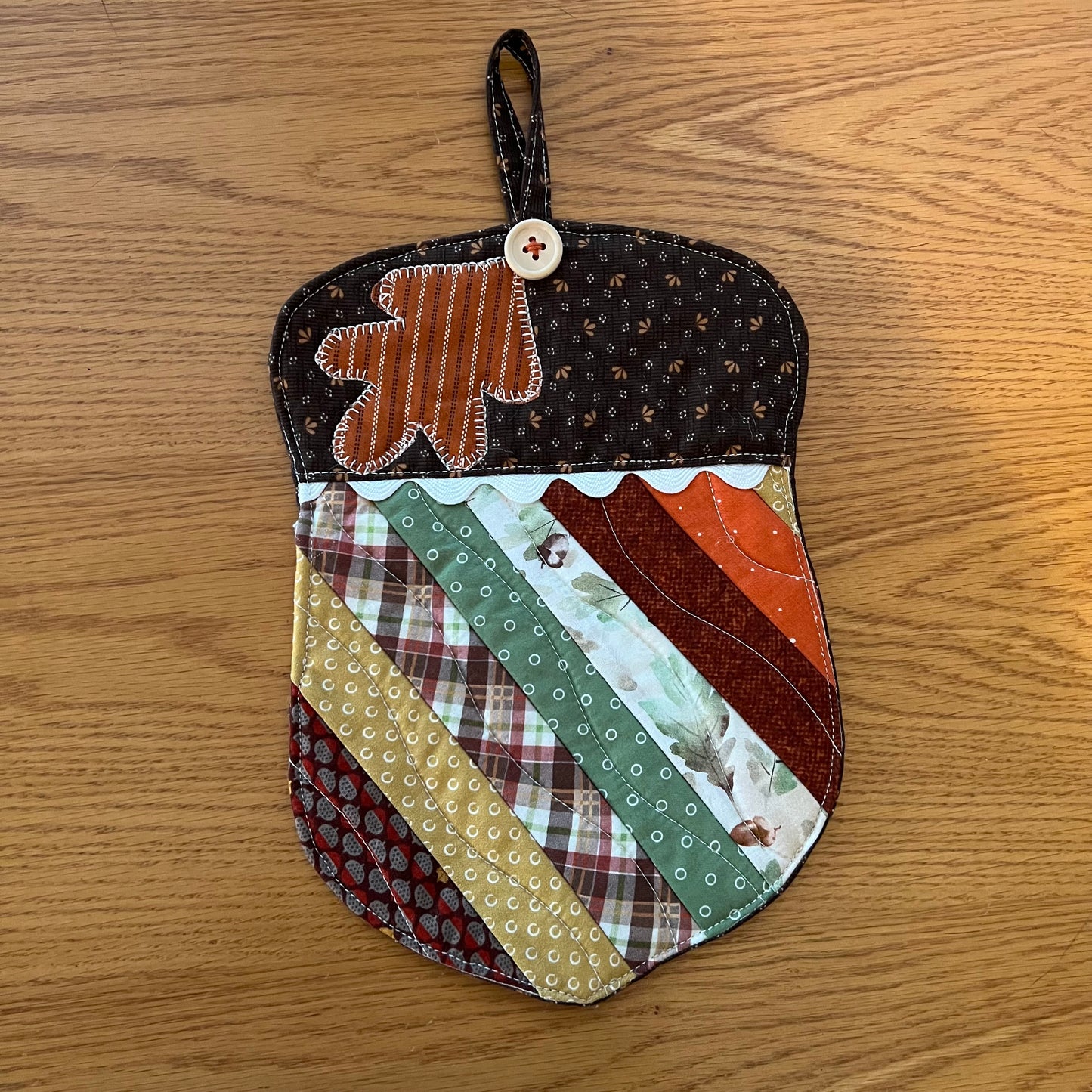 Option A: One Eclectic Spruce acorn-shaped quilted potholder with autumn-themed patchwork fabrics, applique leaf design, wood button, rick rack detailing, and hanging loop. 