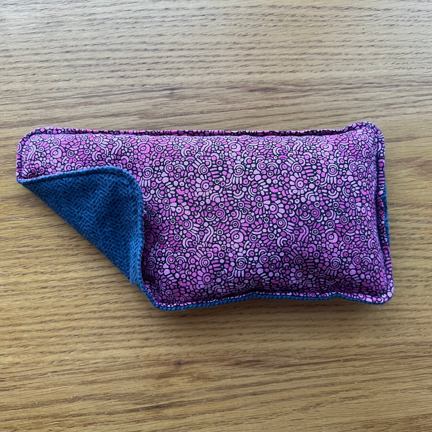 Dual-sided Weighted Eye Pillow with small geometric pink circles on the cotton side and herringbone navy blue pattern on the flannel side.