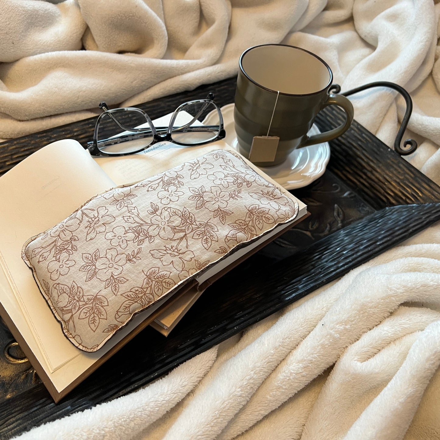Tray with book, Weighted Eye Pillow, and mug on a soft blanket.