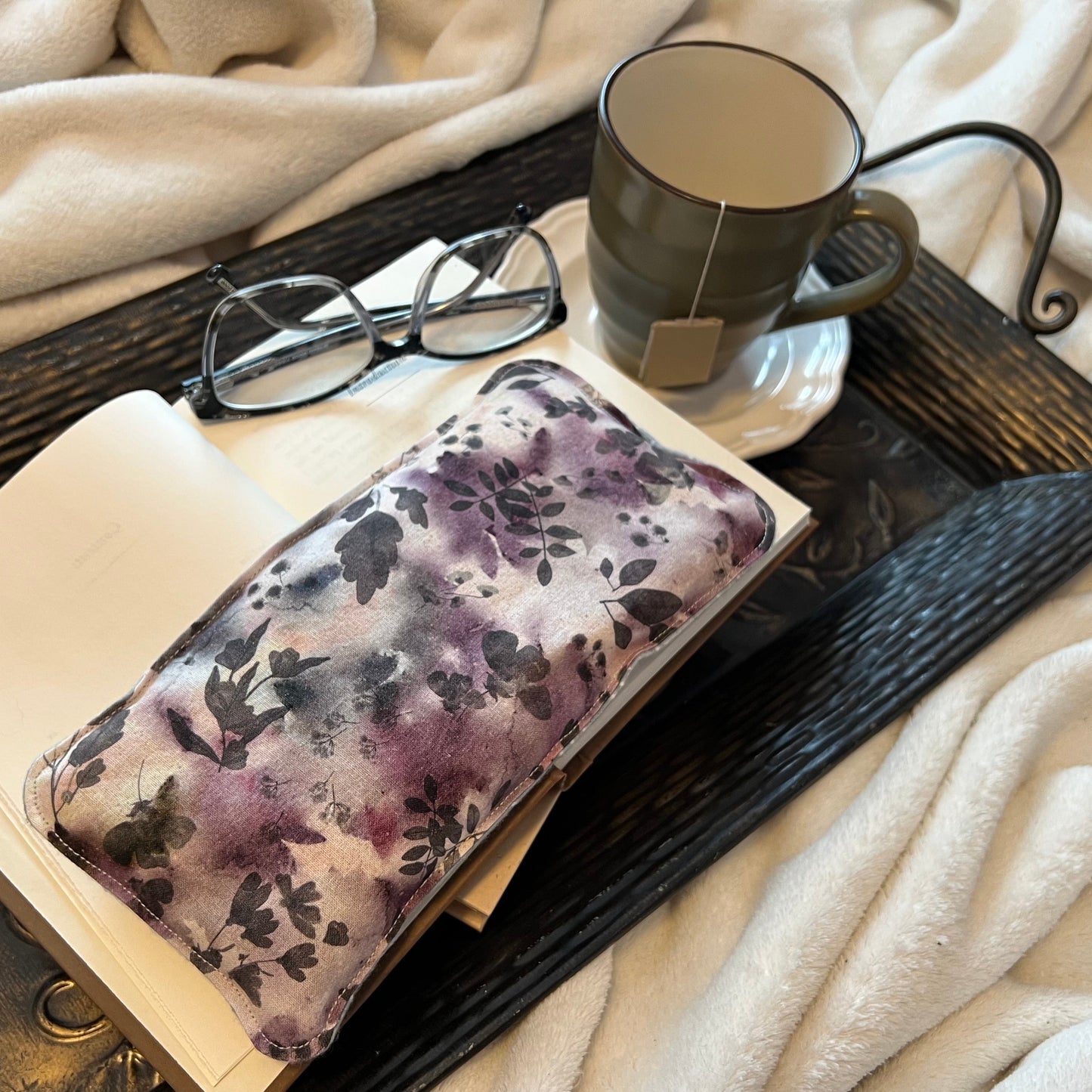 Tray with book, Weighted Eye Pillow, and mug on a soft blanket.