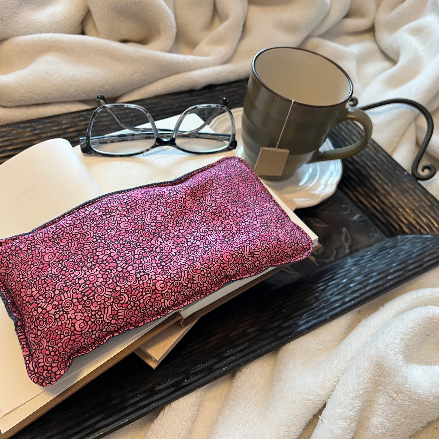 Tray with book, Weighted Eye Pillow, and mug on a soft blanket