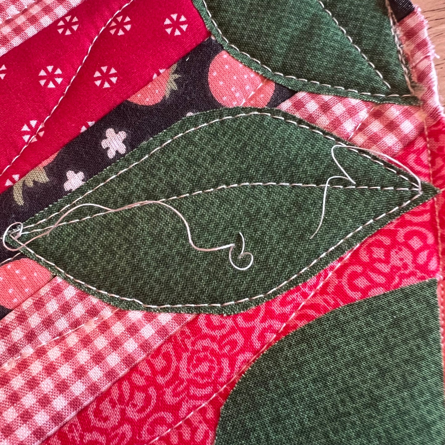 A close-up of the applique process as leaves are being added to the potholder.
