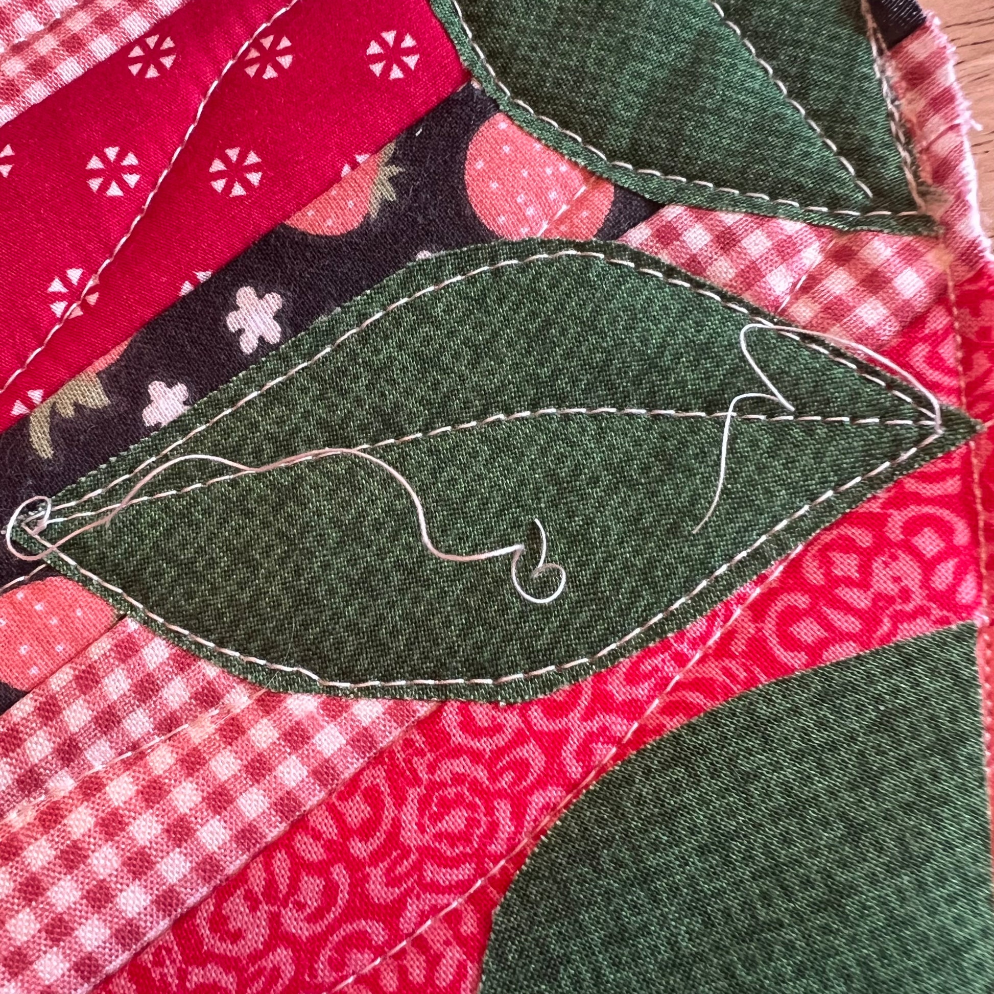 A close-up of the applique process as leaves are being added to the potholder.