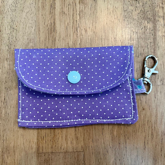 Eclectic Spruce handcrafted mini snap wallet keychain with a snap button closure made of purple cotton fabric with white polka dots, featuring a light blue snap button, and a silver metal swivel clasp.