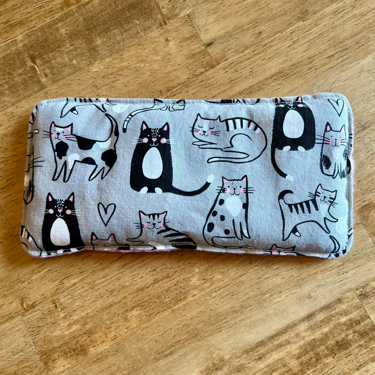 Dual-sided Purrfect Pause Weighted Eye Pillow by Eclectic Spruce. It features a  light gray background and a playful print of black, white, and pink cats.
