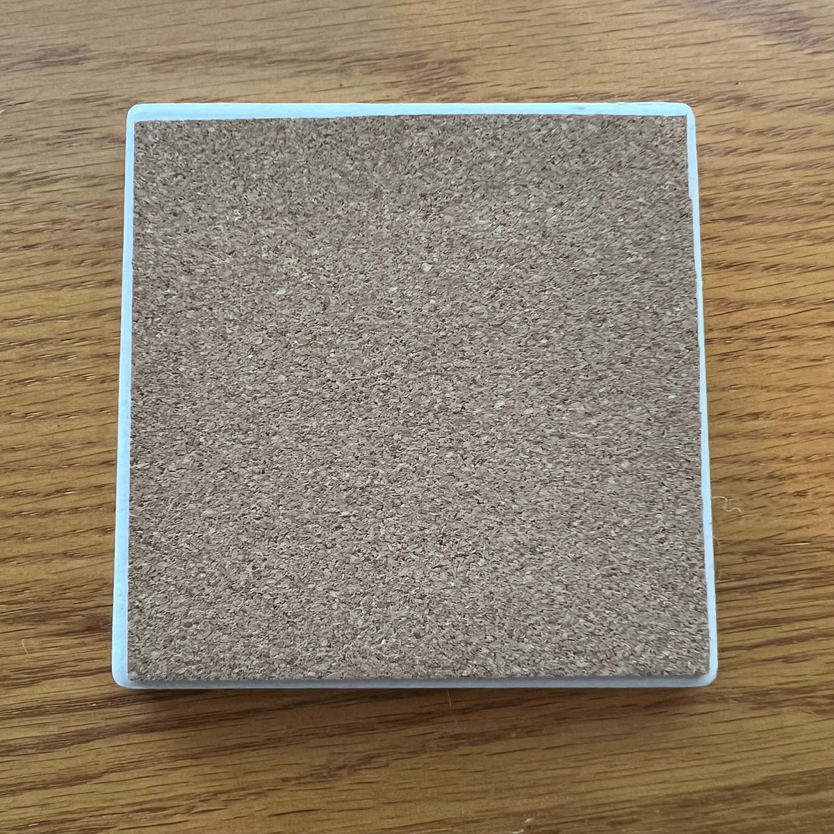 Eclectic Spruce's ceramic coasters have a cork backing to protect your furniture. This photo shows the cork backside of one coaster.
