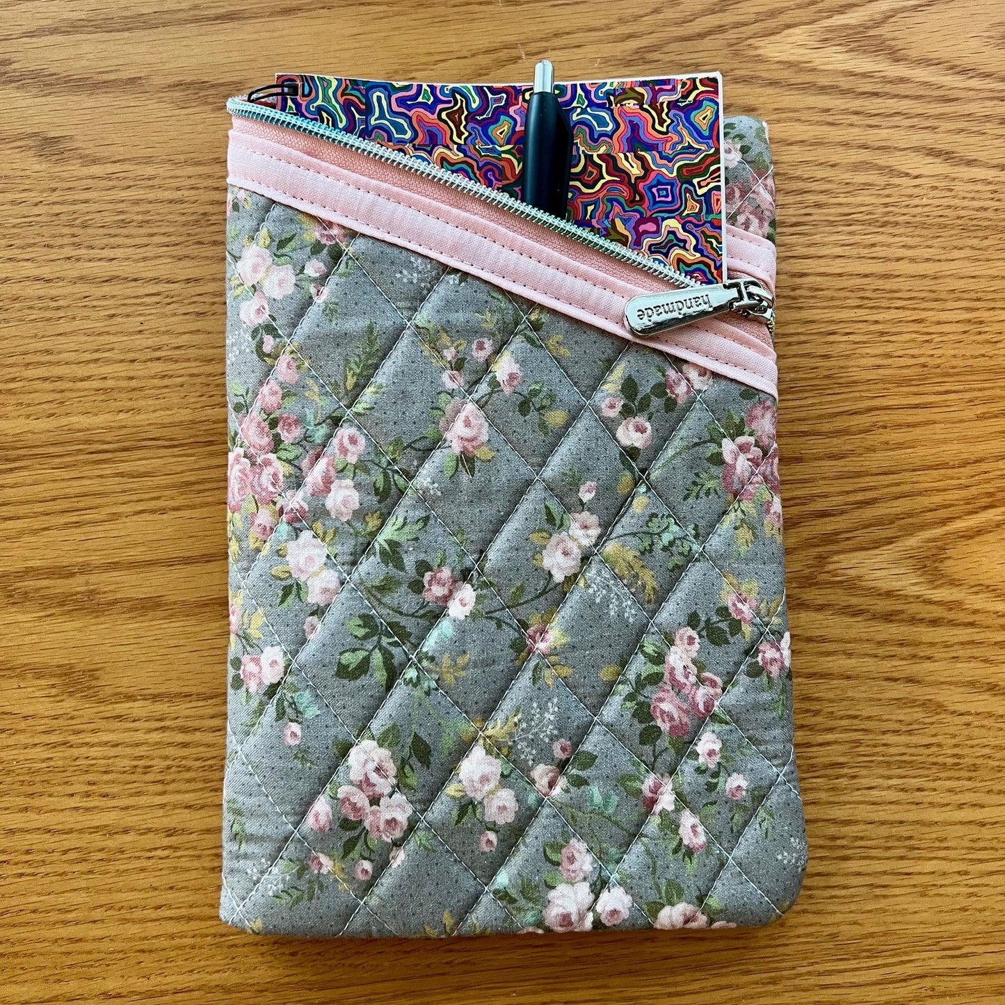 Floral quilted zipper pouch filled with a journal and pen.