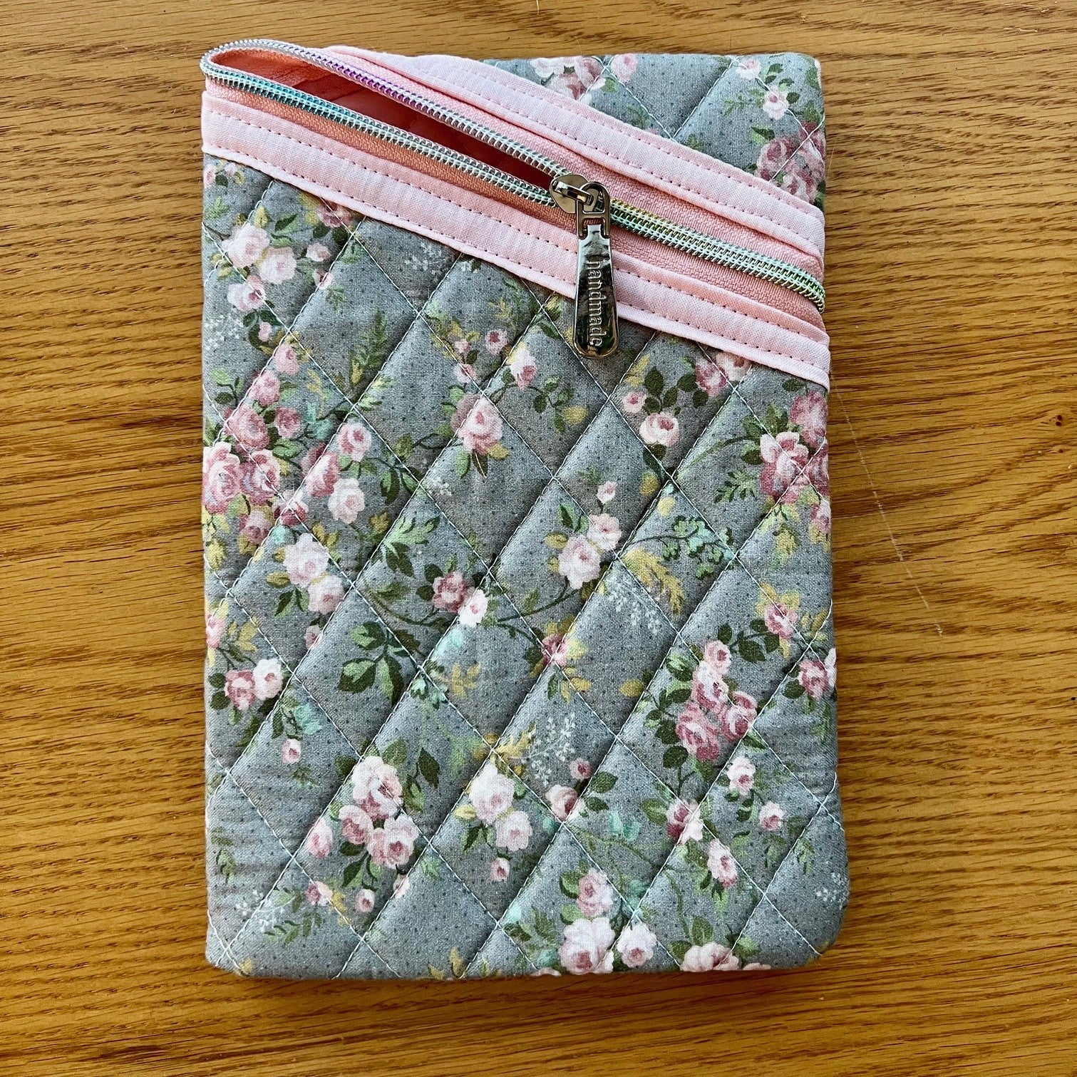 Floral quilted zipper pouch on a wooden surface.