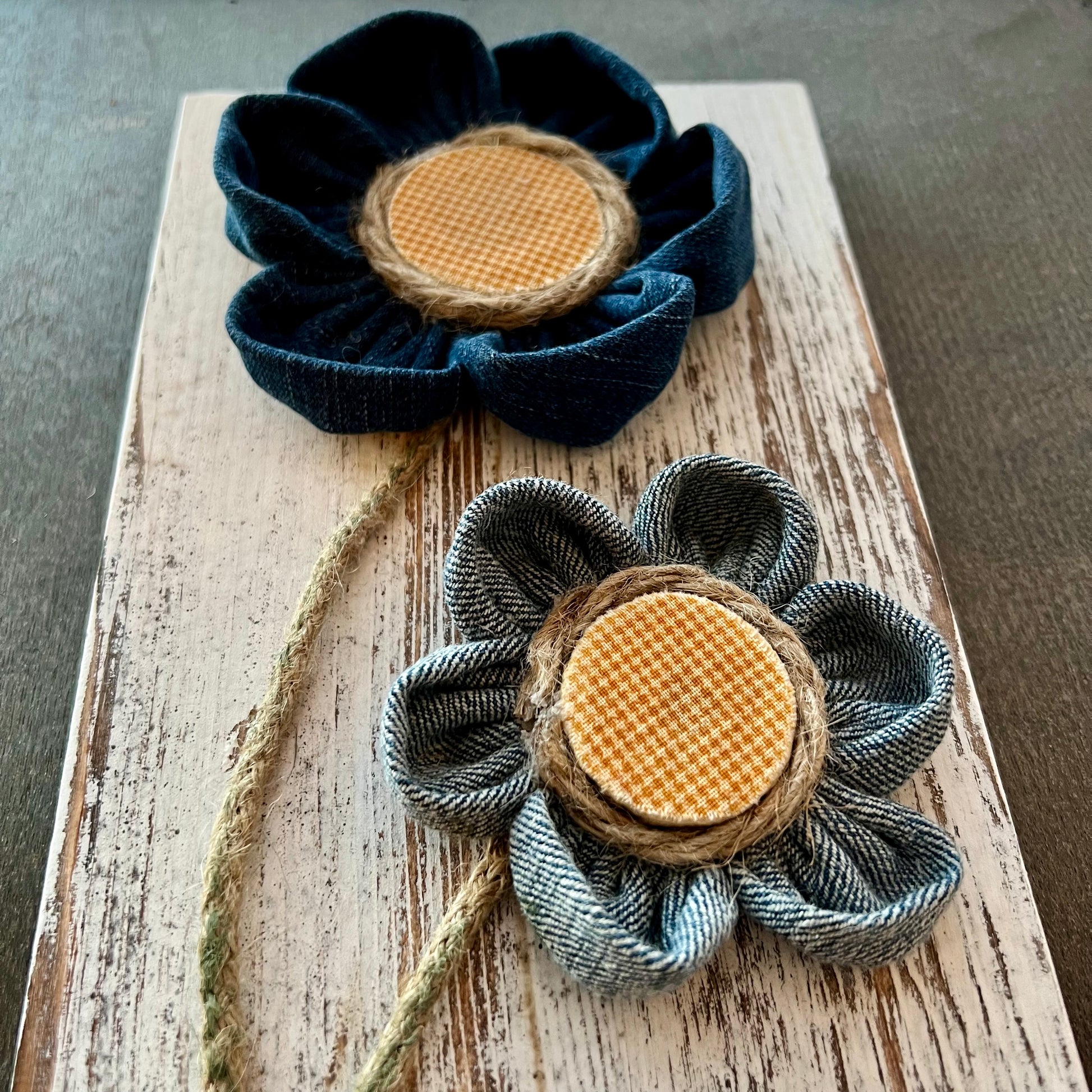 Close-up of the 3D botanical wall art featuring yellow gingham and reclaimed denim flowers on a white-washed wood plank.