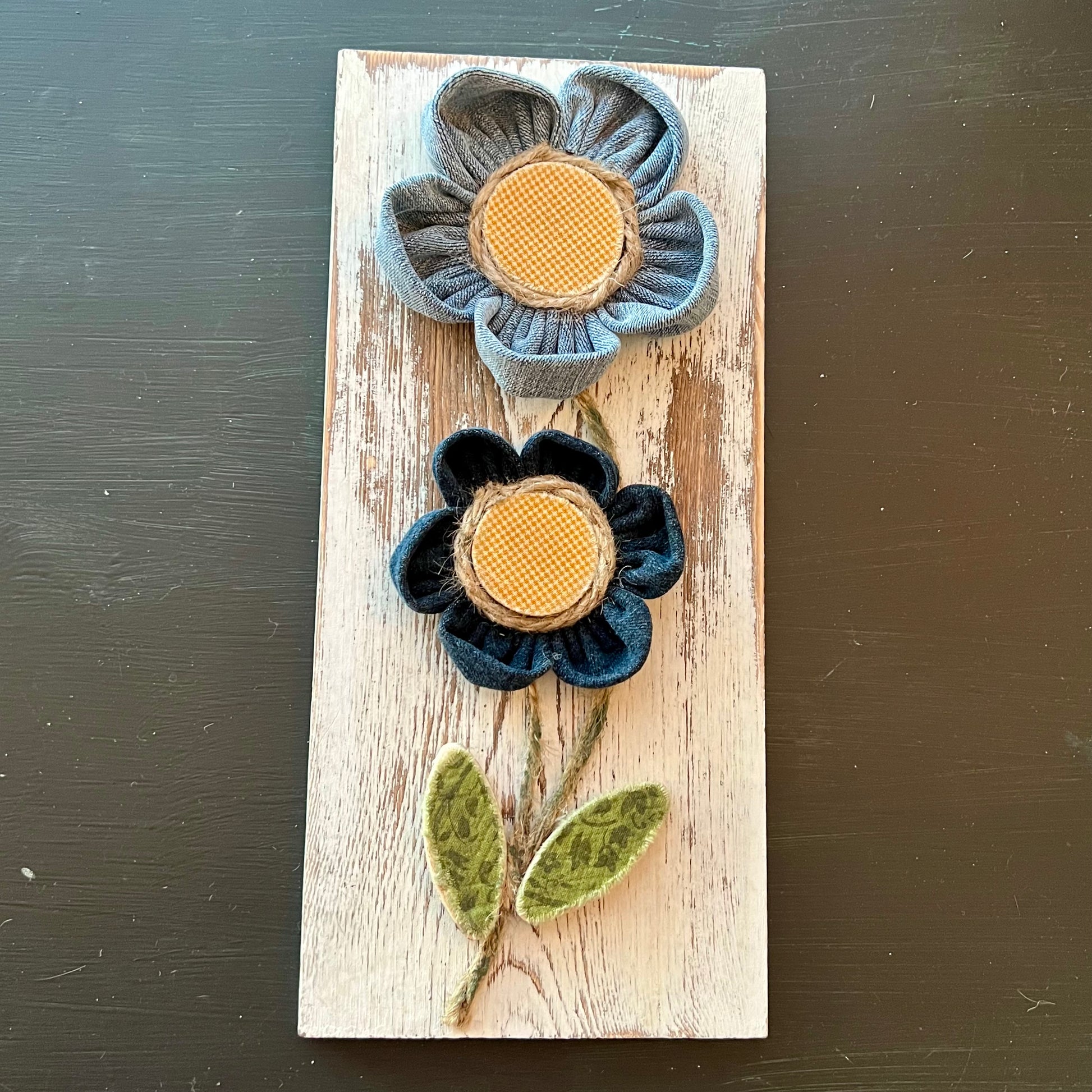 3D botanical wall art featuring yellow gingham and reclaimed denim flowers on a white-washed wood plank.