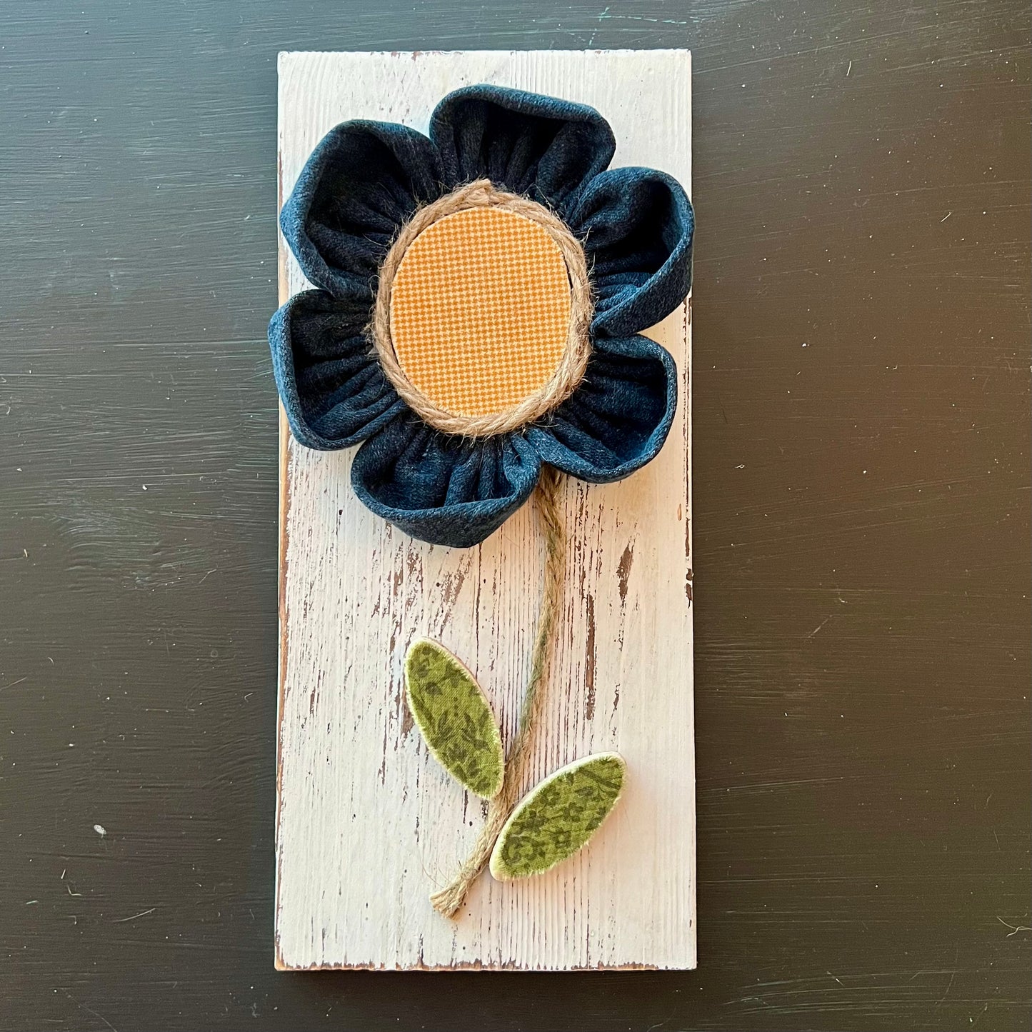 3D botanical wall art featuring yellow gingham and reclaimed denim flowers on a white-washed wood plank.