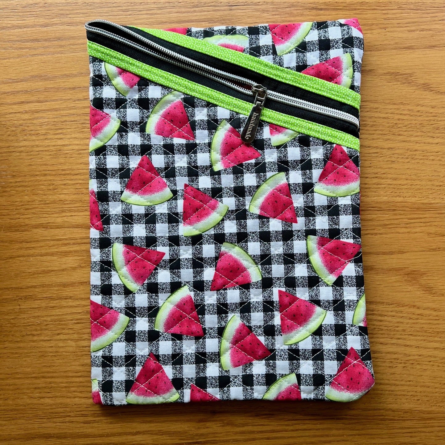 Quilted zipper pouch with featuring a fabric that has watermelon slices over a black and white buffalo check pattern.
