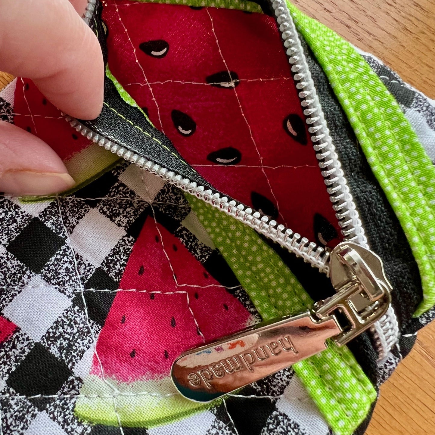 The inside of the quilted zipper pouch is pink and seeded like the inside of a watermelon.