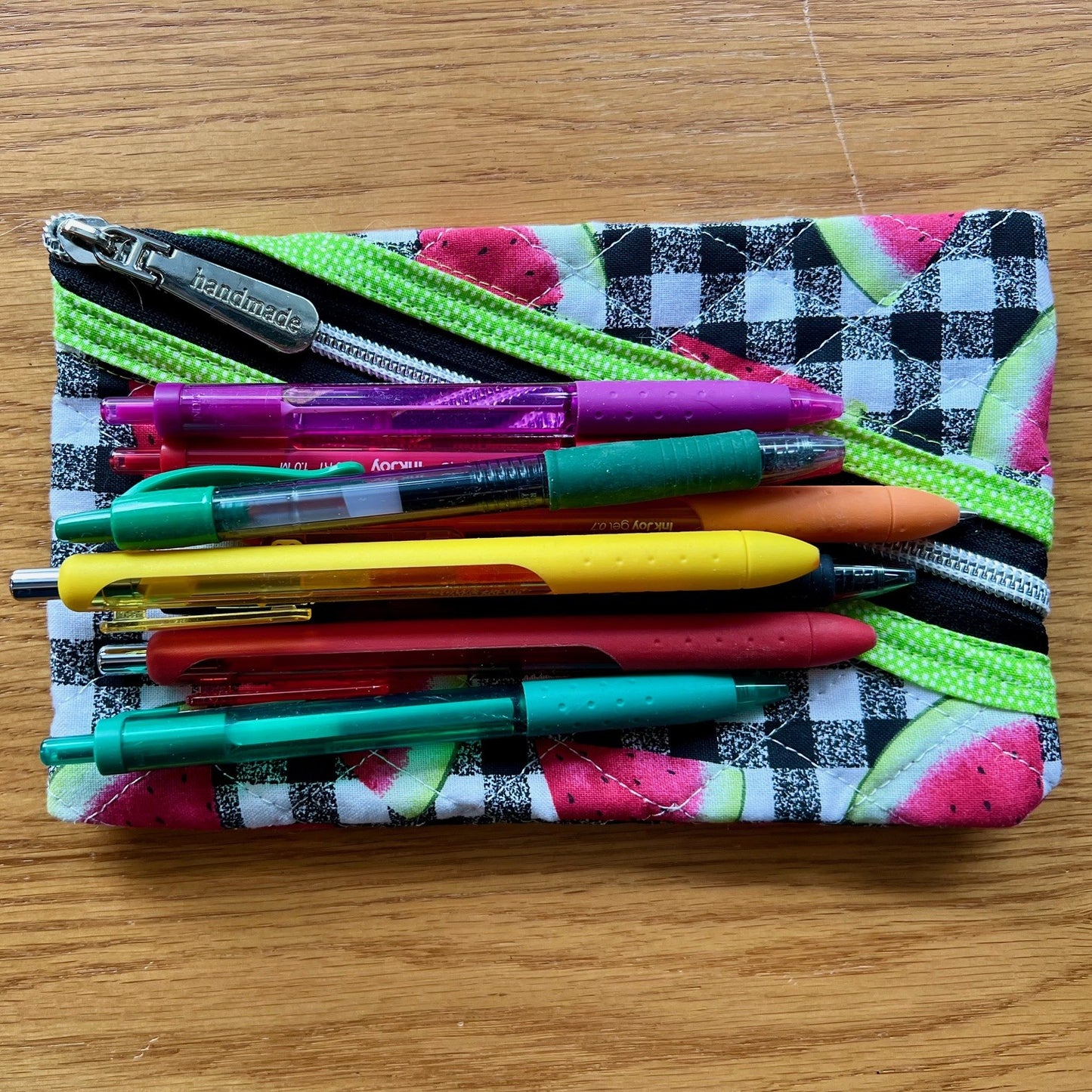 Quilted zipper pouch with pens on top of it to show sizing.