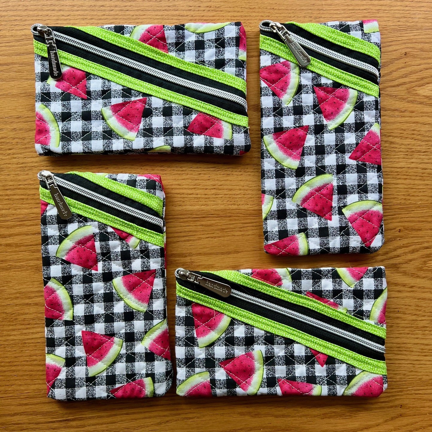 Small quilted zipper pouches with fabric featuring watermelon slices on top of a black and white buffalo check pattern.