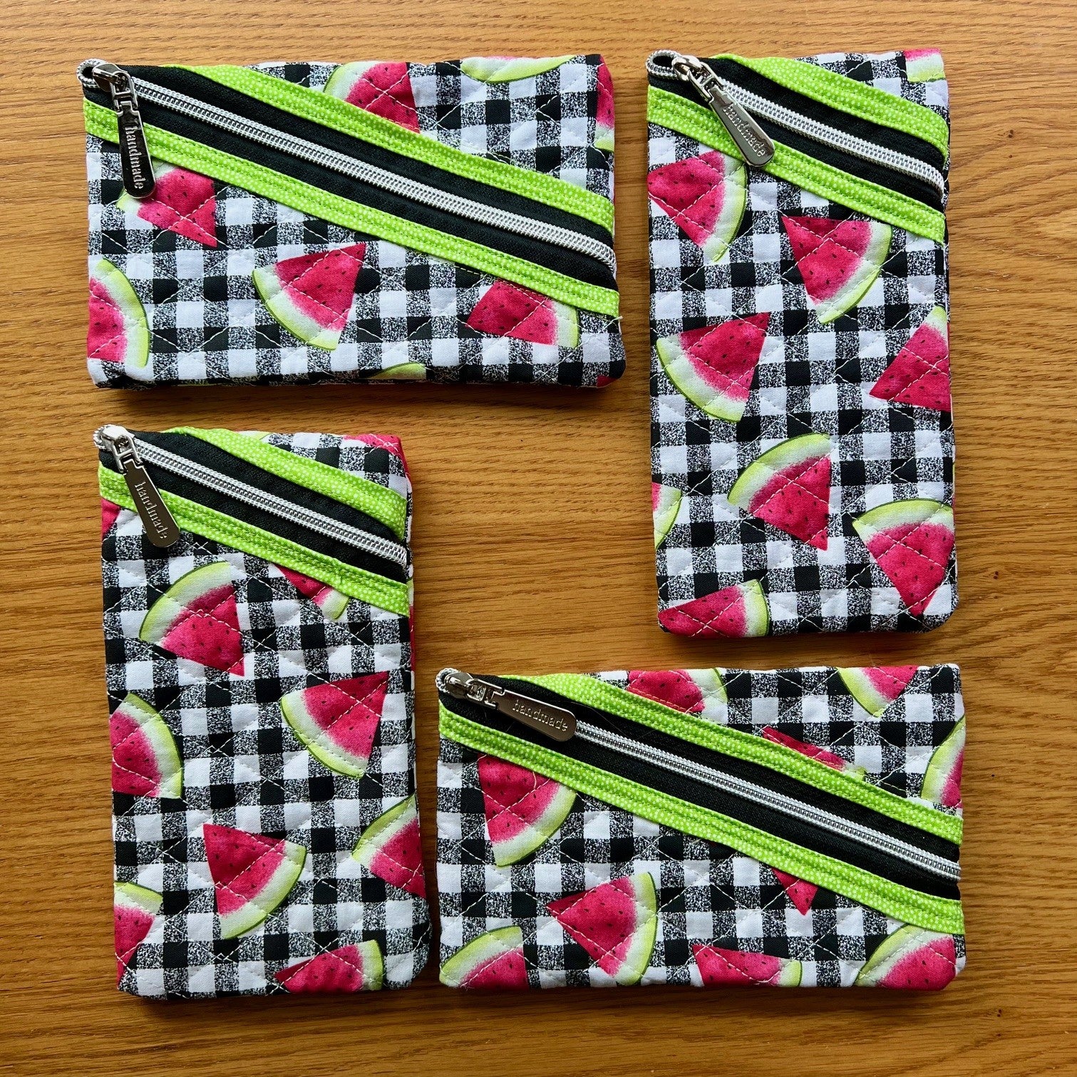 Small quilted zipper pouches with fabric featuring watermelon slices on top of a black and white buffalo check pattern.