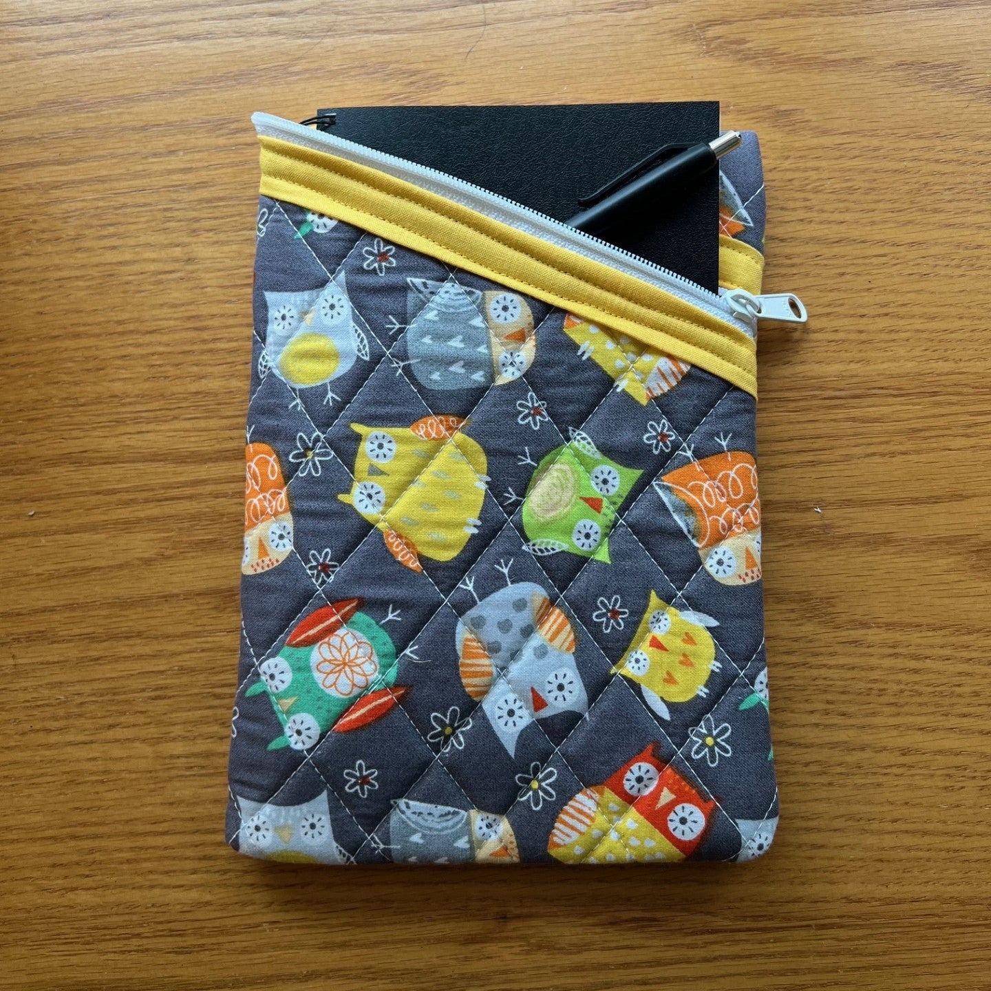 Quilted zipper pouch filled with a journal and pen.